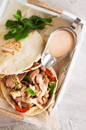 Greek pita bread with meat and salad on wooden tray. Space for text. Selective focusの写真素材