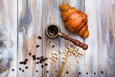 Morning coffee and fresh croissant on wooden table. Top view. Cozy breakfast. Flat lay styleの写真素材