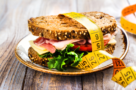 Delicious sandwich with measure tape on wooden table. Healthy eating or diet conceptの写真素材