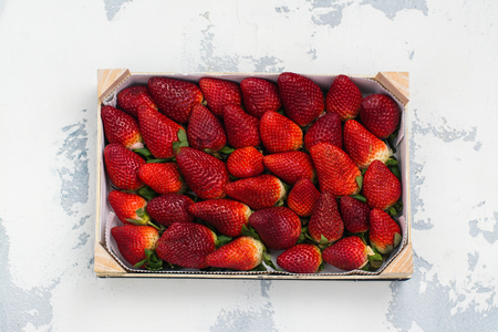Fresh organic strawberry in a wooden box on white stone background. Space for text. Top viewの写真素材