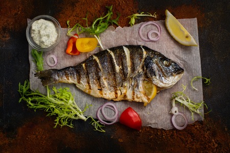 Delicious grilled dorado with vegetables and tartar sauce overs rust stone table. Space for textの写真素材