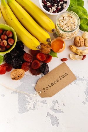 Products rich of potassium (K). Bananas, spinach, nuts, grains, dried fruits overs stone table. Space for textの写真素材