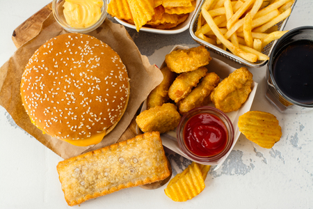 Junk food on white table. Fast carbohydrates not good for health, heart and skinの写真素材