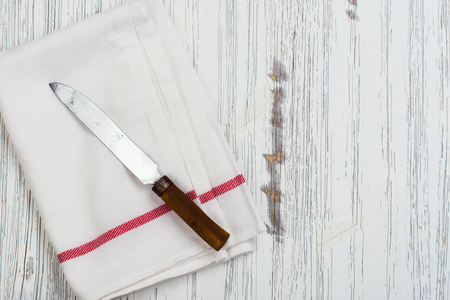 Linen kitchen towel and knife on white wooden table. Space for textの写真素材