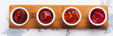 Bowls of various tomato sauces on white stone table. Top view. Copy spaceの写真素材