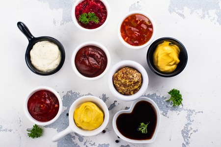 Various sauces and dips in porclean bowls on white stone background. Copy spaceの写真素材
