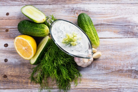 Greek tzatziki sauce with ingredients on kitchen wooden table. Copy spaceの写真素材