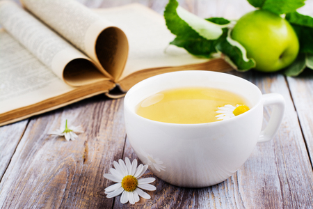 Cup of hot tea, old vintage book and apple on wooden table. Magic cozy reading concept. Copy spaceの写真素材