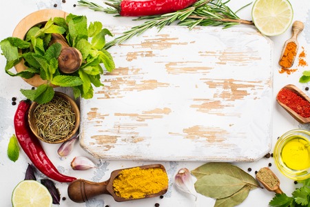 Selection of herbs, spices and wooden cutting board on white stone table. Copy spaceの写真素材