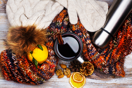 Cold weather walking set: warm clothes, hot mulled wine and thermos flask on wooden background. Healthy lifestyle conceptの写真素材