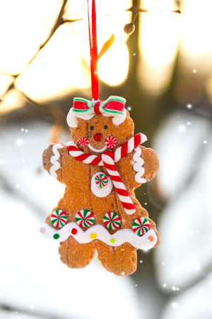 Christmas greeting card with gingerbread man cookie toy hanging on a tree branchの写真素材