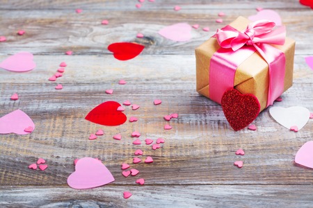 Gift box with pink bow ribbon and glitter hearts on wooden rustic backgroundの写真素材