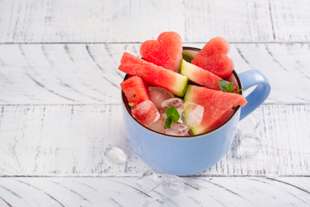Watermelon slices in a blue porcelain cup on white wooden tableの写真素材