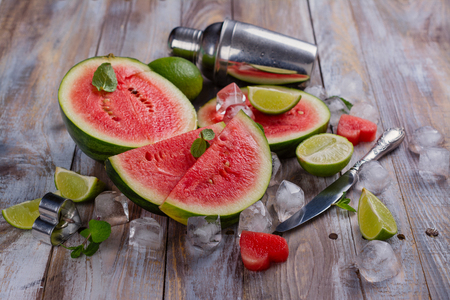 Fresh ripe watermelon slices, lime and mint on wooden tableの写真素材