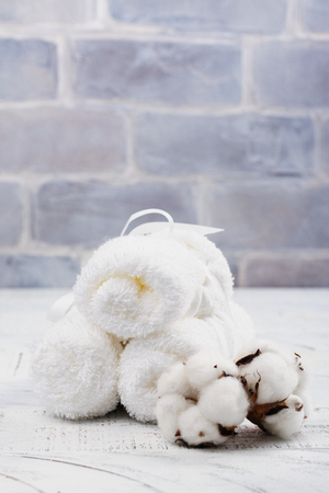 White cotton towels and branch of cotton on wooden tableの写真素材