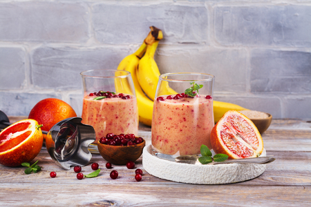 Healthy refreshing pink smoothie with apple, red oranges, cowberry and branの写真素材