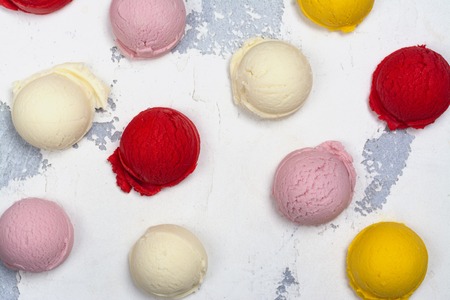 Orange, vanilla, raspberry and strawberry ice cream scoops on white backgroundの写真素材