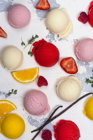 Orange, vanilla, raspberry and strawberry ice cream scoops on white backgroundの写真素材