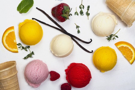 Orange, vanilla, raspberry and strawberry ice cream scoops on white backgroundの写真素材