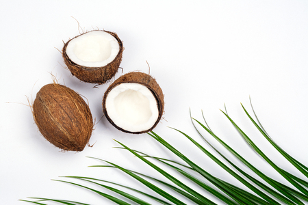 Coconut halves and leaves on white backgroundの写真素材