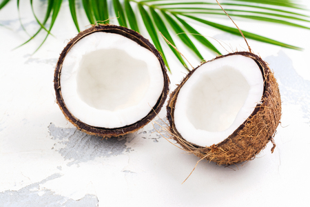 Coconut halves and leaves on white backgroundの写真素材
