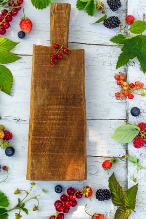 Wooden board and garden berries on summer backgroundの写真素材