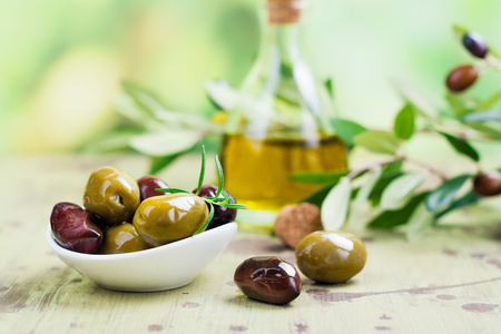 Olive oil in a glass bottle, green and black olivesの写真素材