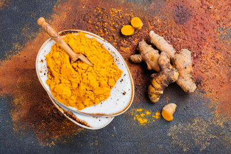 Turmeric powder and fresh turmeric on grunge dark backgroundの写真素材