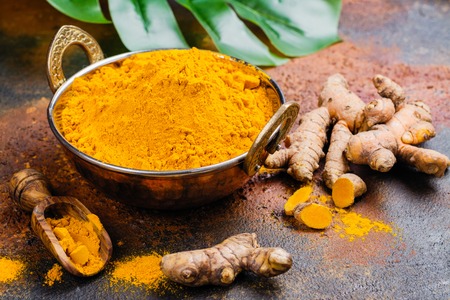 Turmeric powder and fresh turmeric on grunge dark backgroundの写真素材