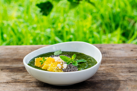 Green smoothie bowl with banana, spinach, chia seeds and orangesの写真素材