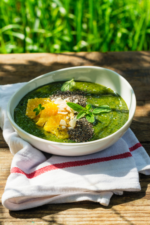 Green smoothie bowl with banana, spinach, chia seeds and orangesの写真素材
