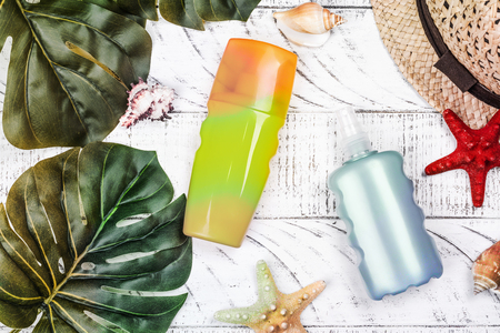 Bottles of sunscreen lotion and moisurizing spray agains sunburn. Summer skincare protection concept. Summer vacation background with tourist accessoriesの写真素材