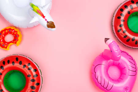 Various inflatable toy rings on pink background. Drinks holders for swimming pool party. Copy spaceの写真素材