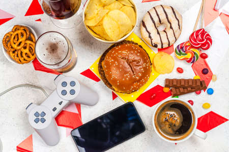 Dopamine fasting background. Life without social media, gadget and food detox concept. Red and white signal ribbon covering junk food and digital devices. Copy spaceの写真素材