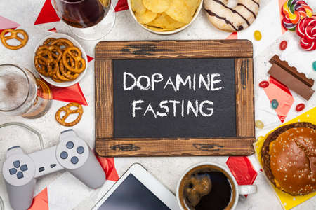 Dopamine fasting background. Life without social media, gadget and food detox concept. Red and white signal ribbon covering junk food and digital devices. Copy spaceの写真素材