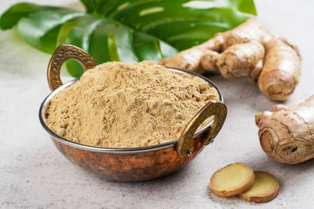 Fresh ginger root and ginger powder in a copper bowlの写真素材