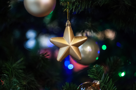 Christmas holiday golden star hanging from the pine tree in front of the silver ball