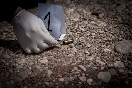 The crime scene, murder, investigation, sleeves shots serve as evidence, the investigation is done, the expert takes the capsule forceps and placed in the bagの写真素材