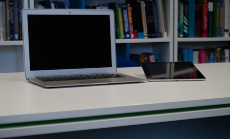 Laptop and tablet  with a blank screen on the white desk table in the libraryの写真素材
