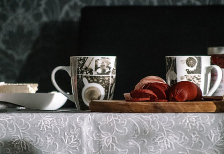 Warm breakfast with tea, dried meet and diary products on the tableの写真素材