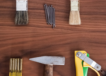 Hammer, nails, brushes, handsaw and meter stick on a wooden table deskの写真素材