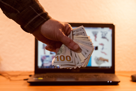 Guy or businessman holding euro money in his hand. Laptop in the backgroundの写真素材
