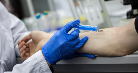 Doctor or scientist inject a needle in patient's armの写真素材