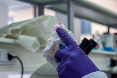 Doctor holding a needle in his hand in which he has blood on the tip of the needle is located drops of bloodの写真素材