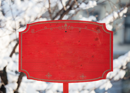 Red holiday Christmas wooden sign mockup empty placeholder entrance exit New Year Santa holiday market in the park during winter snow treesの写真素材
