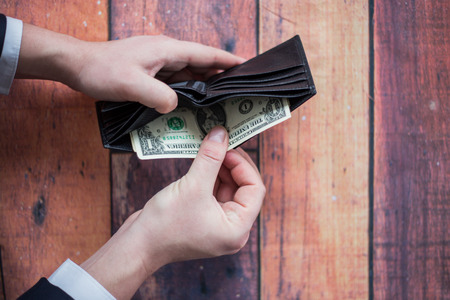 Money in a wallet, a man in a suit at a table, holds a wallet in his hands, a businessman