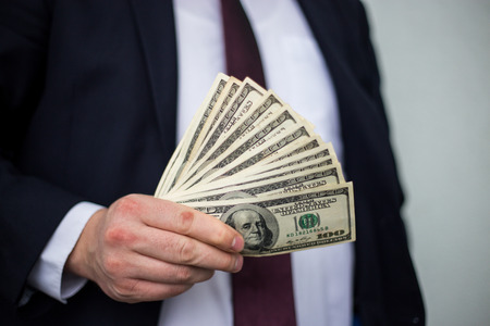 Business Man Displaying a Spread of Cash over a white vintage background