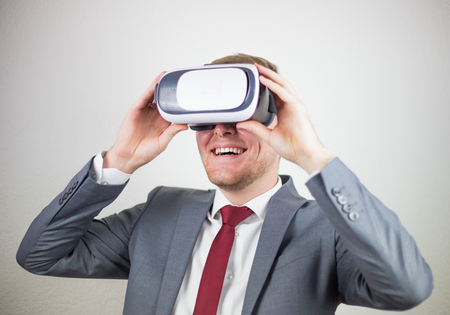 A businessman in a suit, with virtual reality glasses on his eyes, a white background, a delight on...