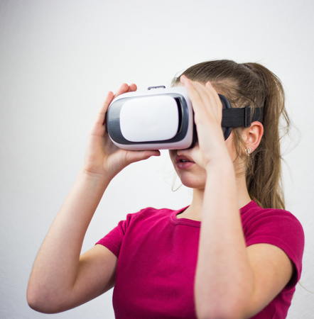 Teenager with virtual reality glasses on the head, enjoying watching, amazing technology, white background, studioの写真素材
