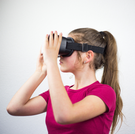 Teenager with virtual reality glasses on the head, enjoying watching, amazing technology, white background, studioの写真素材